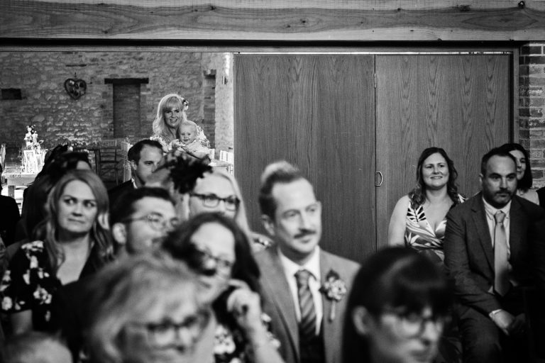 Candid photo of baby at the back of the wedding barn.