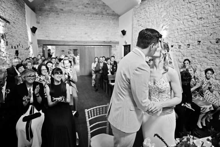 B&W storytelling photo of bride and groom kissing after being announced husband and wife.