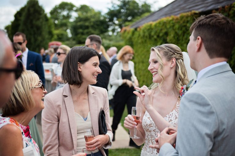 Documentary style wedding photography of guests chatting and laughing with the bride.