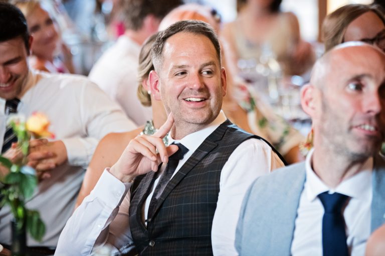 Storytelling photo of guest laughing at wedding speech.