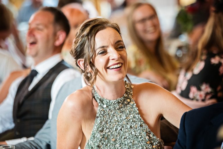 Candid photo of guest laughing at wedding speech.