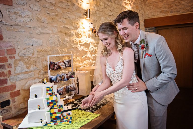 Bride and groom cut a Lego wedding cake.
