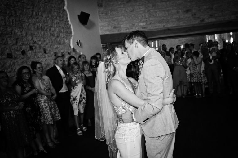 B&W photo of bride and groom kissing during their first dance.
