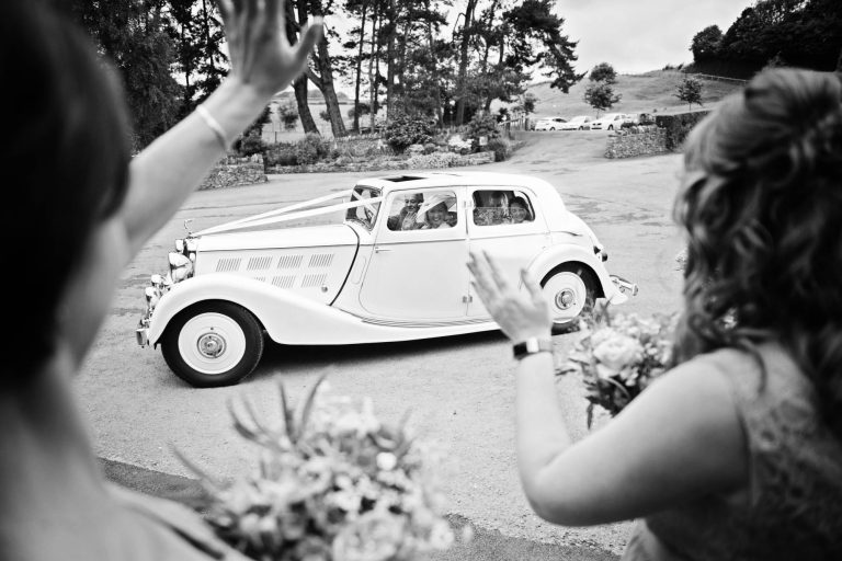 Wedding car and team bride arrive for a wedding at Kingscote Barn