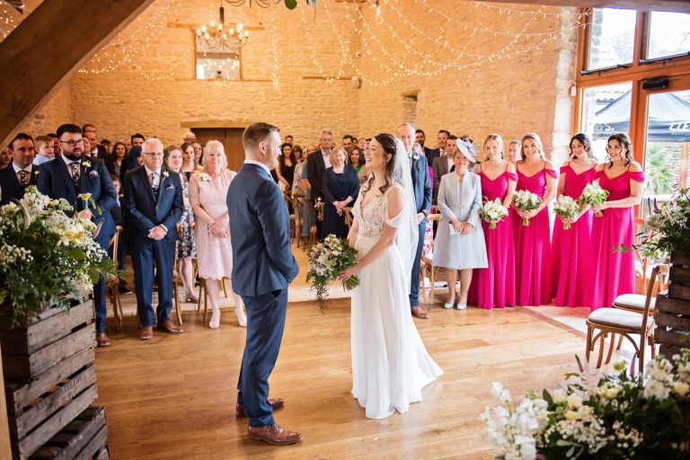 Indoor wedding ceremony in rustic Kingscote Barn