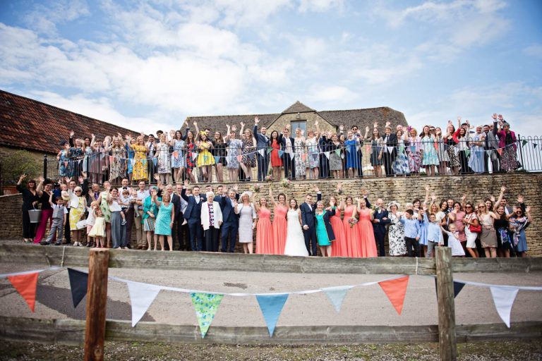 Group photo of everyone waving at Cotswolds wedding venue Kingscote Barn