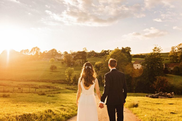 Natural sunset and bride and groom looking back at Kingscote Barn