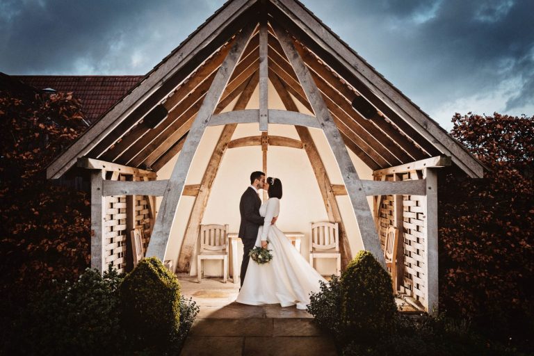 Kingscote Barn bride and groom kissing in the linhay