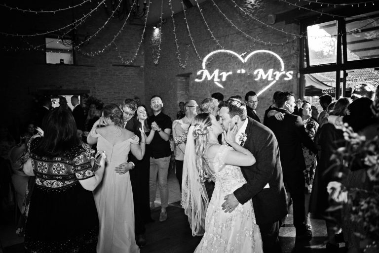 Bride and groom kiss after first dance at Kingscote Barn