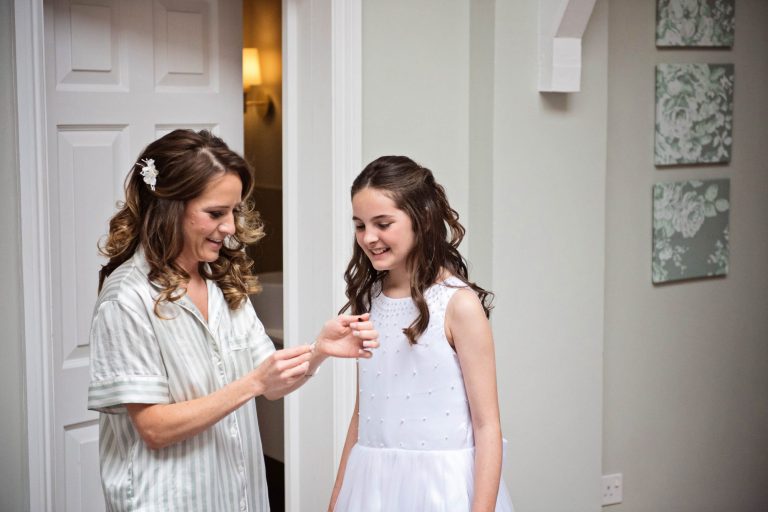 Bride with flower girl looking at the neckless.