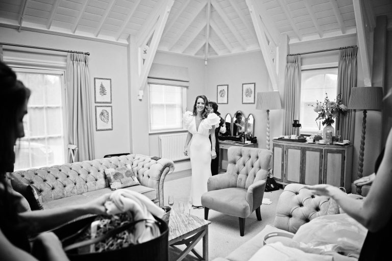 B&W photo of bride getting into her wedding dress.