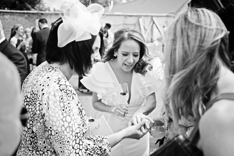 B&W photo of wedding guest looking at Brides new wedding ring.