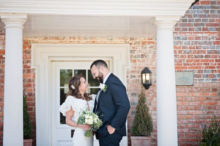 Bride and groom look at each other at the front door at Syrencot.
