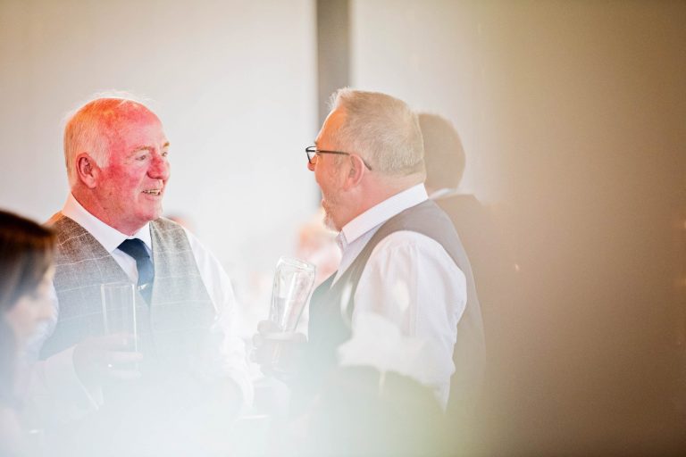 Candid photo of wedding guests chatting during the wedding breakfast.