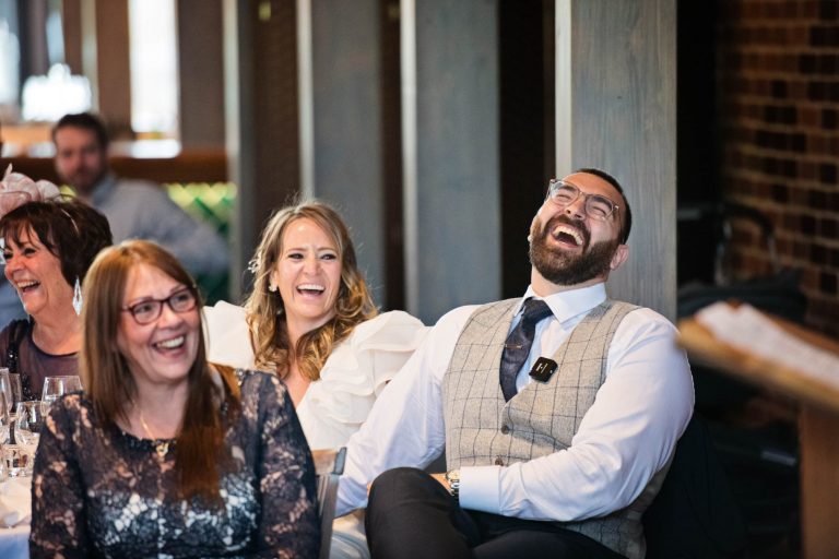 Groom laughing during speeches.