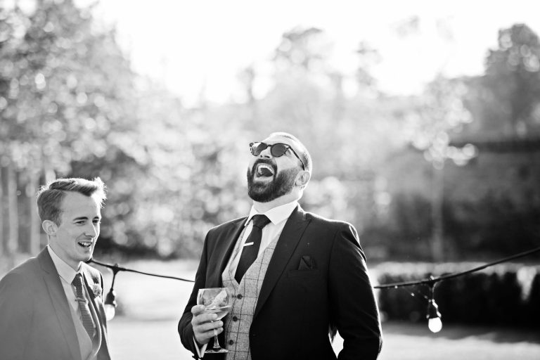 B&W candid photo of the groom laughing.