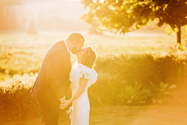 Golden hour photo of wedding couple kissing in the grounds at Syrencot.