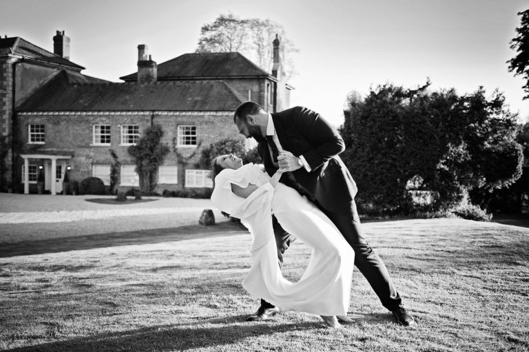 Bride and groom doing the dip in front of the main house at Syrencot. B&W image.