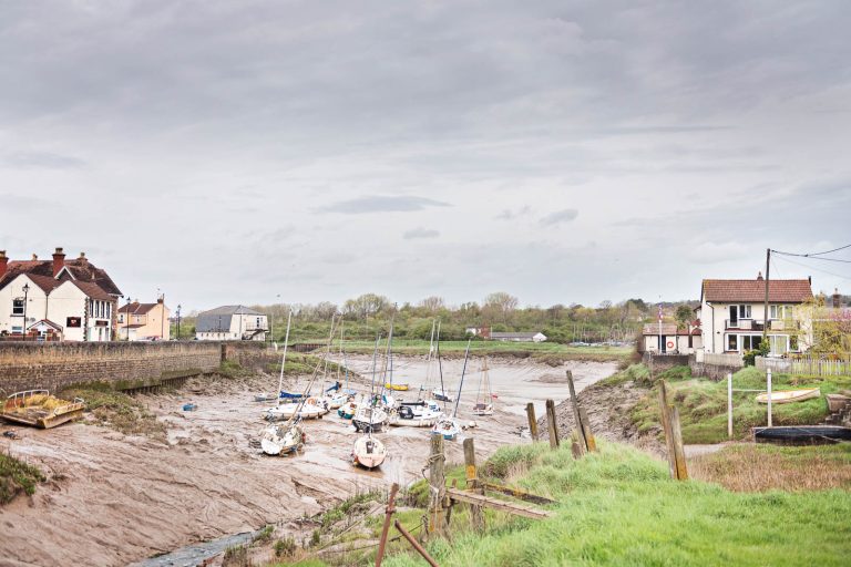 Pill, North Somerset by the father of the groom. Boats lay on the mud in the estuary and houses on either side of the estuary. Looks a postcard but Photograph by Blooming Photography.