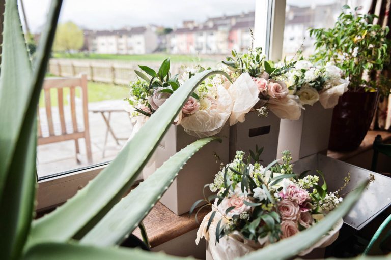 Wedding bouquets (four) in boxes on a window seat in Pill, Plants including a aloe vera on either side. North Somerset. Photograph by Blooming Photography.