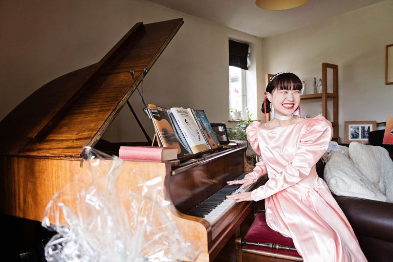 A Japanese girl smiling as she play's the grand piano. Photograph by Blooming Photography.