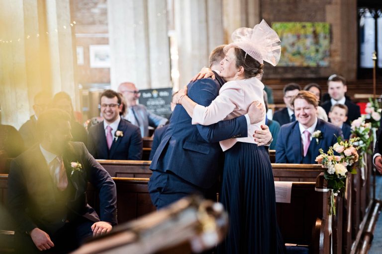 The groom hugs is mother. Candid photograph by Blooming Photography.