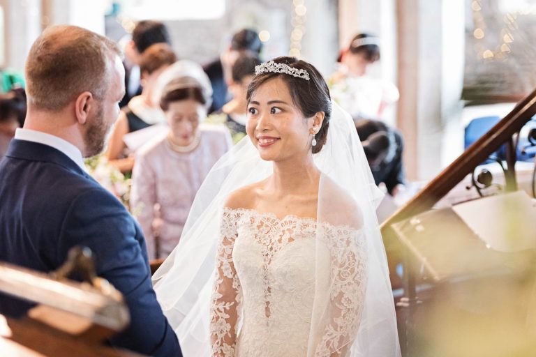 The bride and groom look at each other during the wedding ceremony. Story telling photograph by Blooming Photography.