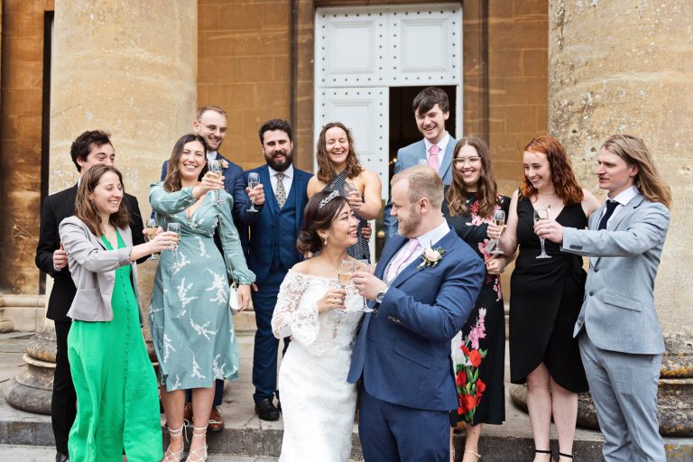 Guests cheer the bride and groom on the steps of Leigh Court. Candid photograph by Blooming Photography.