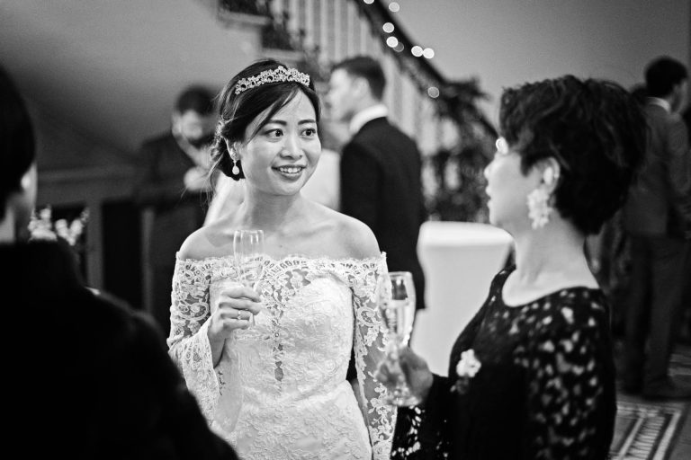 Candid black and white photograph at Leigh Court of bride chatting to guests by Blooming Photography.