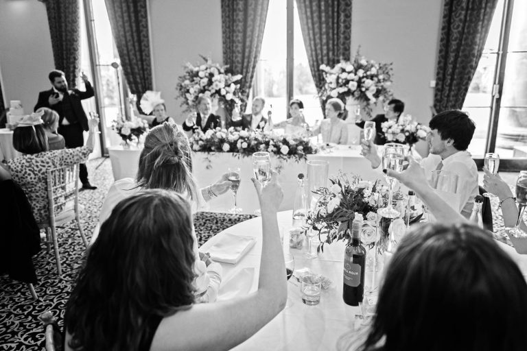 Guests totast the end of speeches with their glasses raised in the Library in Leigh Court, Bristol. Photo by Blooming Photography.