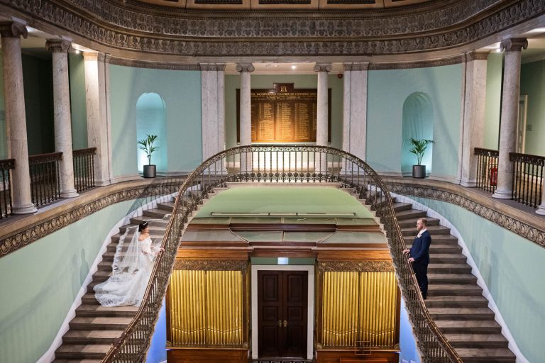 Bride and groom on the steps in the great hall at Leigh Court, Bristol. Photograph by Blooming Photography