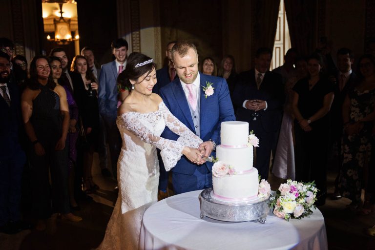Bride and groom cut the cake in the tapestry room in Leigh Court, Bristol. Photo by Blooming Photography.