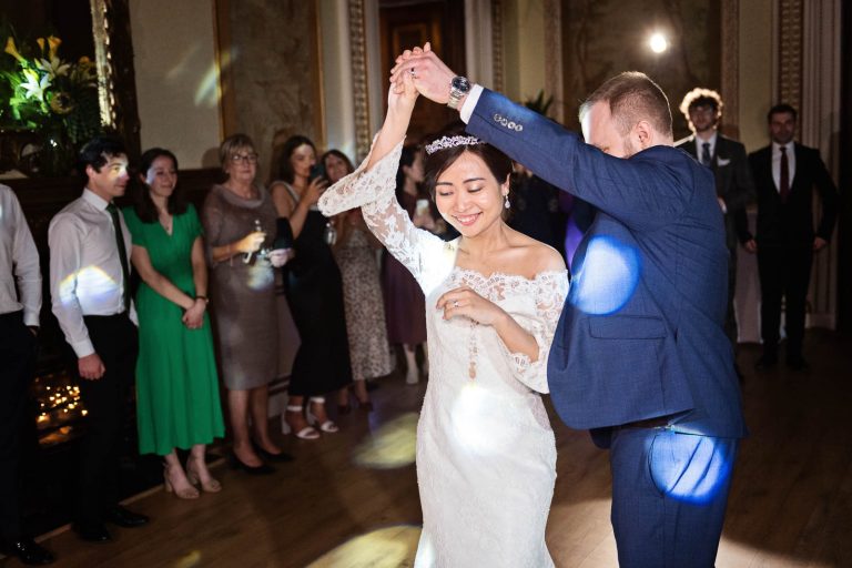 Bride and groom do their first dance in the tapestry room in Leigh Court, Bristol. Bride doing a twirl. Photo by Blooming Photography.