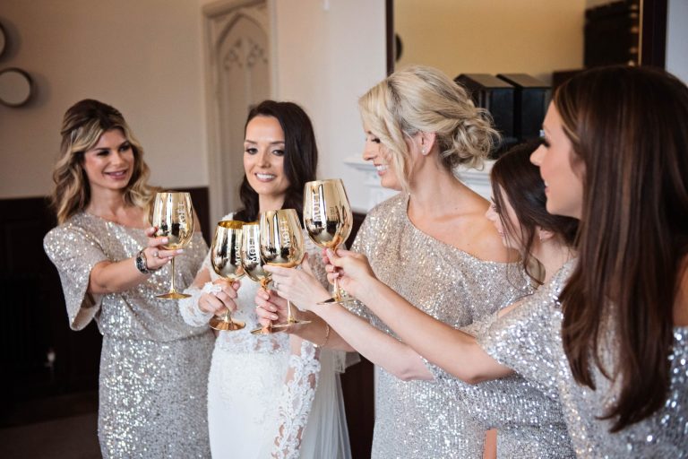 Photo of the bride and her bridesmaids raising a glass together.