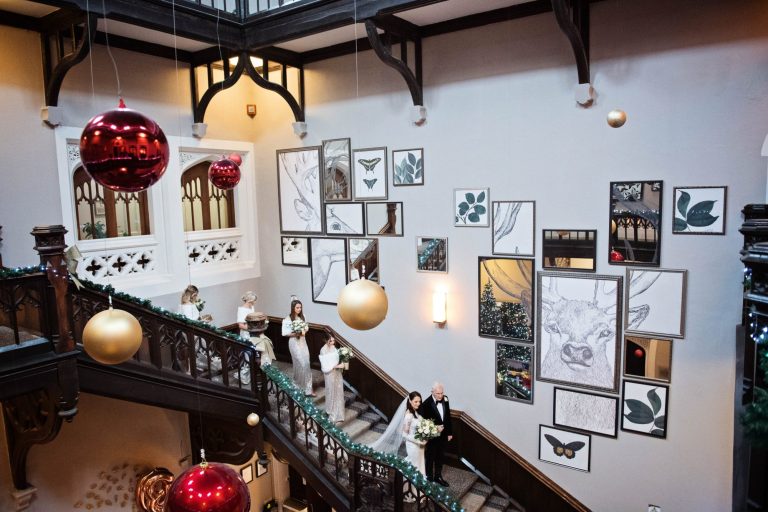 Bride walking down the stairs with her father and bridesmaids at Tortworth Court