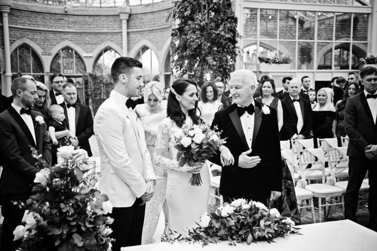 B&W documentary photo of bride being given away by her father at a wedding at the Orangery at Tortworth Court.