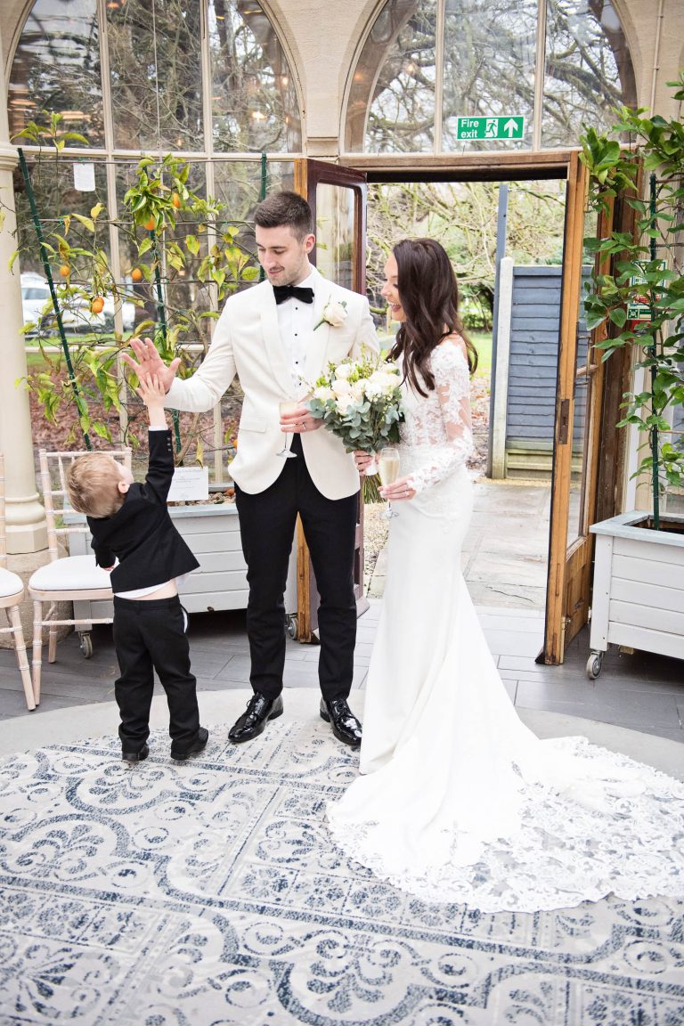 Portrait photo of the groom being high fived by a page boy.