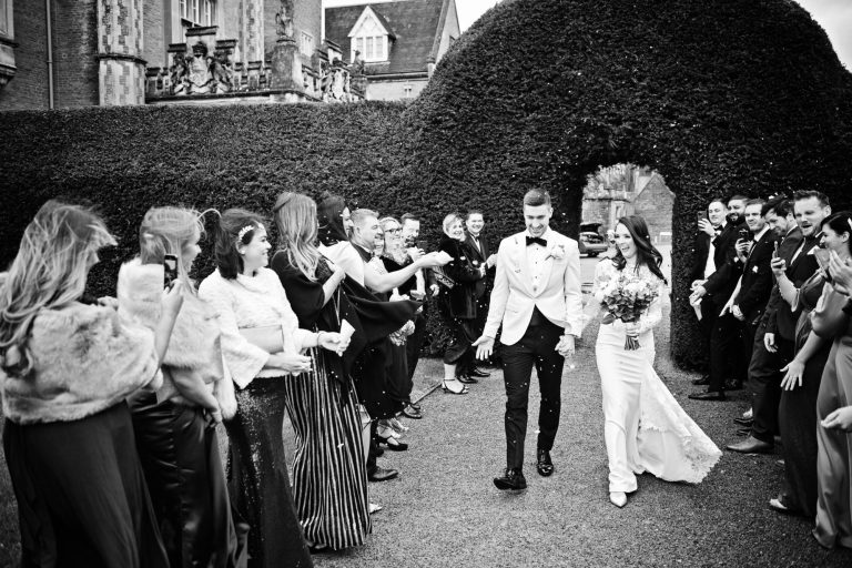 B&W documentary photo of bride and groom getting showered by confetti during their winter wedding at Tortworth Court Hotel.
