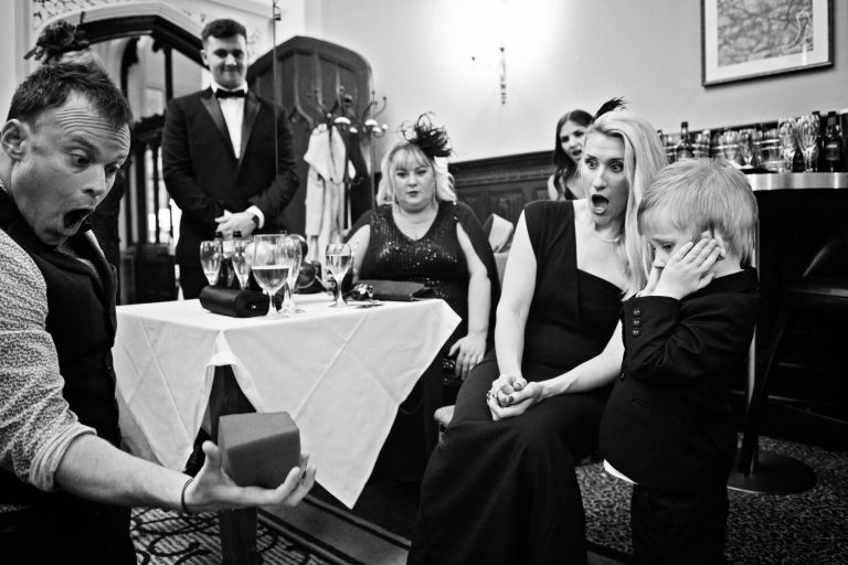 Candid photo of magician doing magic tricks in front of wedding guests.