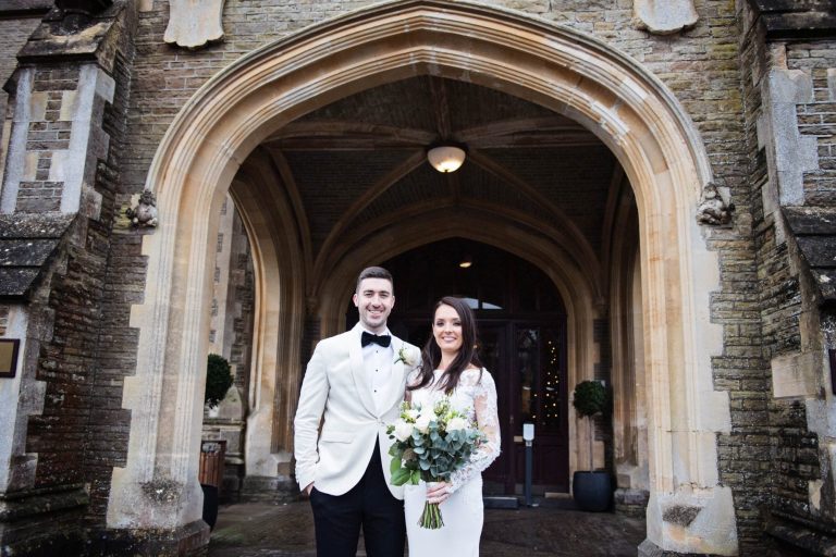 Bride and groom stand in front of the arch at Tortworth Court.