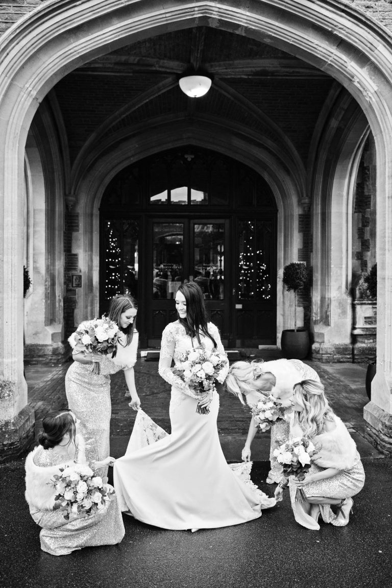 Portrait of the bridal party looking after the brides wedding dress out the front of Tortworth Court.