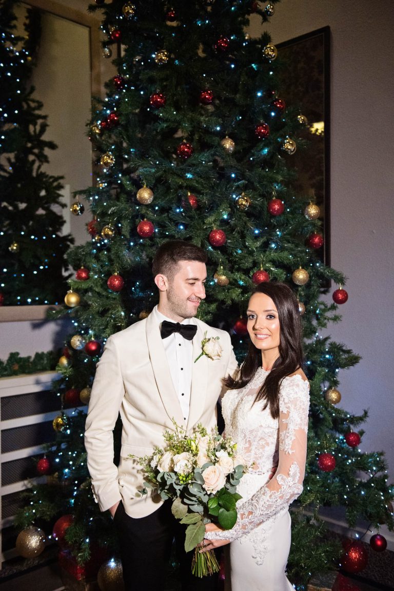 Portrait photo of bride and groom standing in front of the Christmas Tree at Tortworth Court Hotel