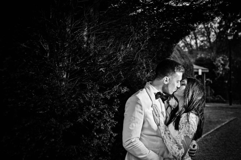B&W photo of the bride and groom kissing in the grounds at the winter wedding at Tortworth Court.