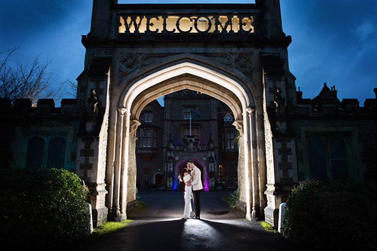 Night time shot of bride and groom with the Welcome Arch lit up at Tortworth Court.