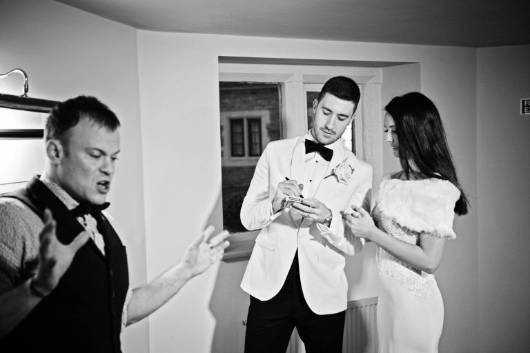 B&W candid photo of bride and groom with magician.