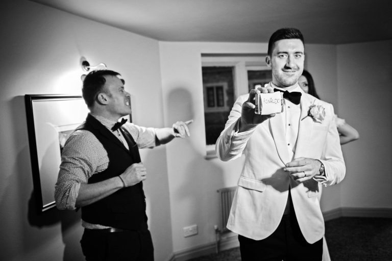 B&W candid photo of bride and groom with magician.