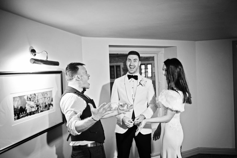 B&W candid photo of bride and groom with magician.
