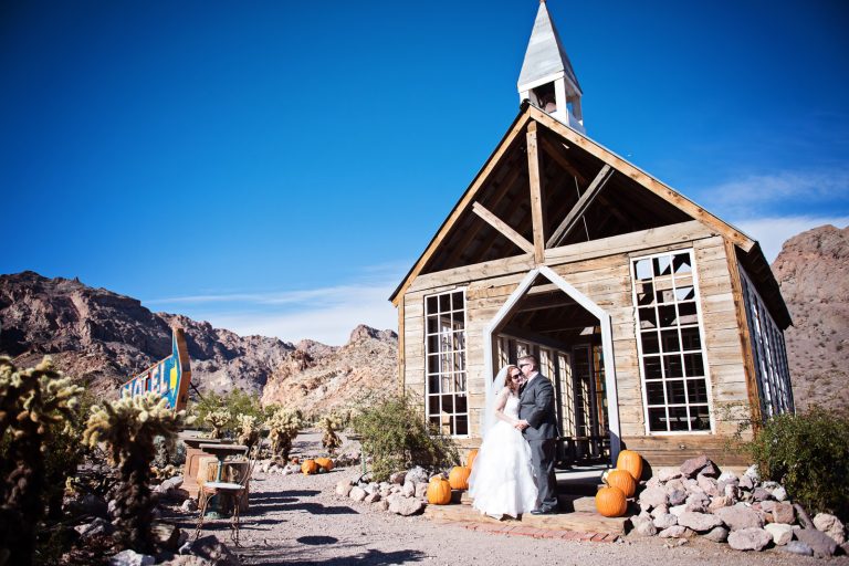 Bride and groom stand in front of a wedding chapel in the Nevada desert at Nelson Ghost Town.
