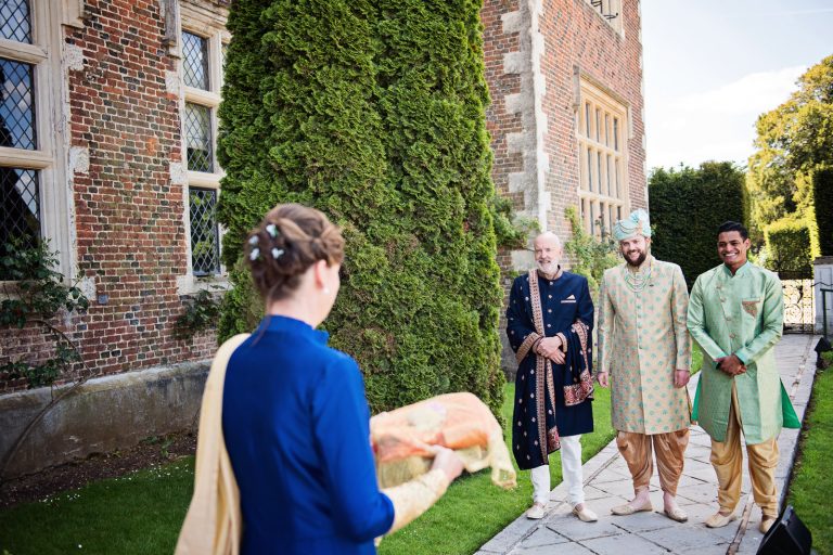Mother of the groom brings wedding attire to the groom and his groomsmen at North Mymms Park, candidly photographed by Blooming Photography.