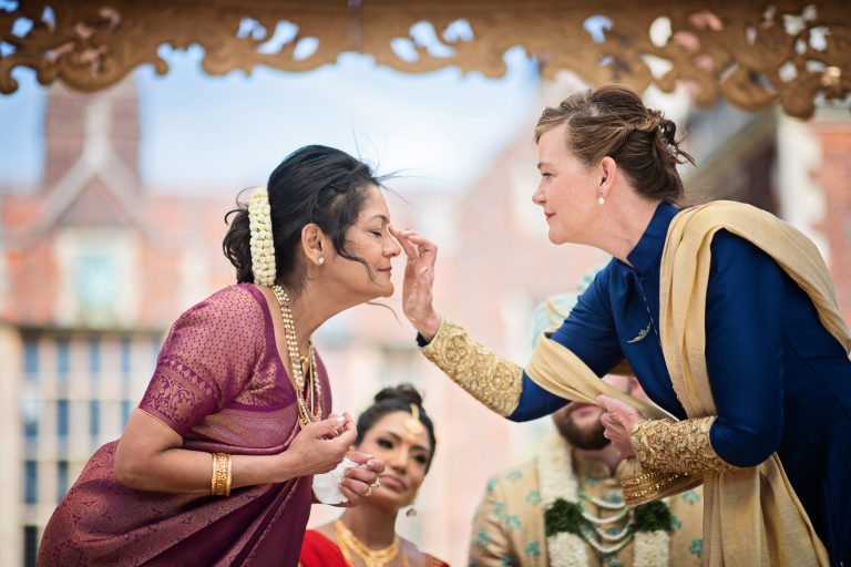 Mother of the bride and mother of the groom exchange bindi during the Indian wedding ceremony, at North Mymms Park, candidly photographed by Blooming Photography.